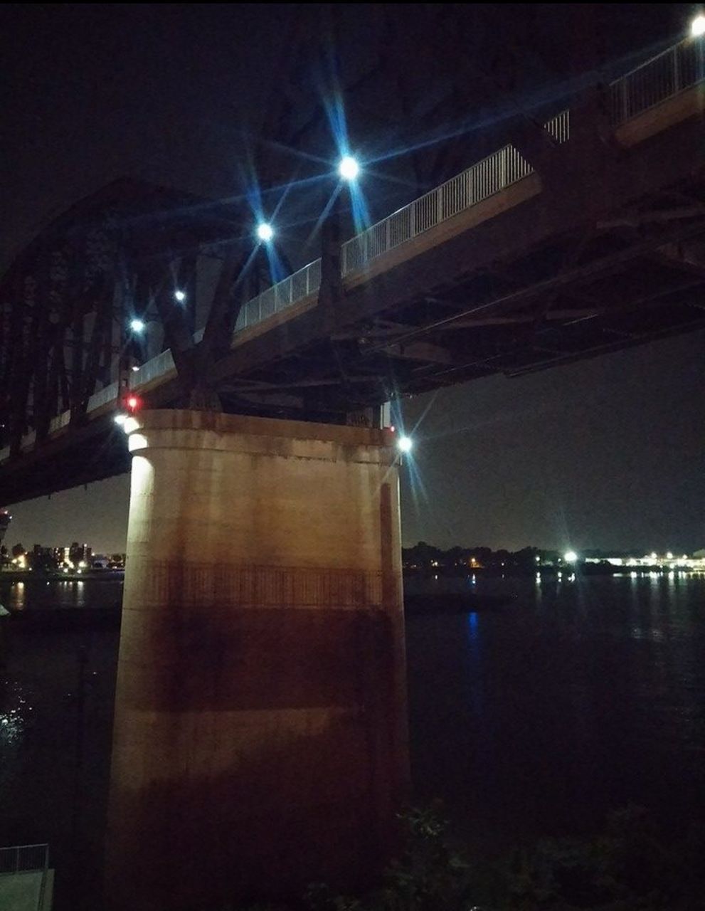 ILLUMINATED BRIDGE OVER RIVER AT NIGHT