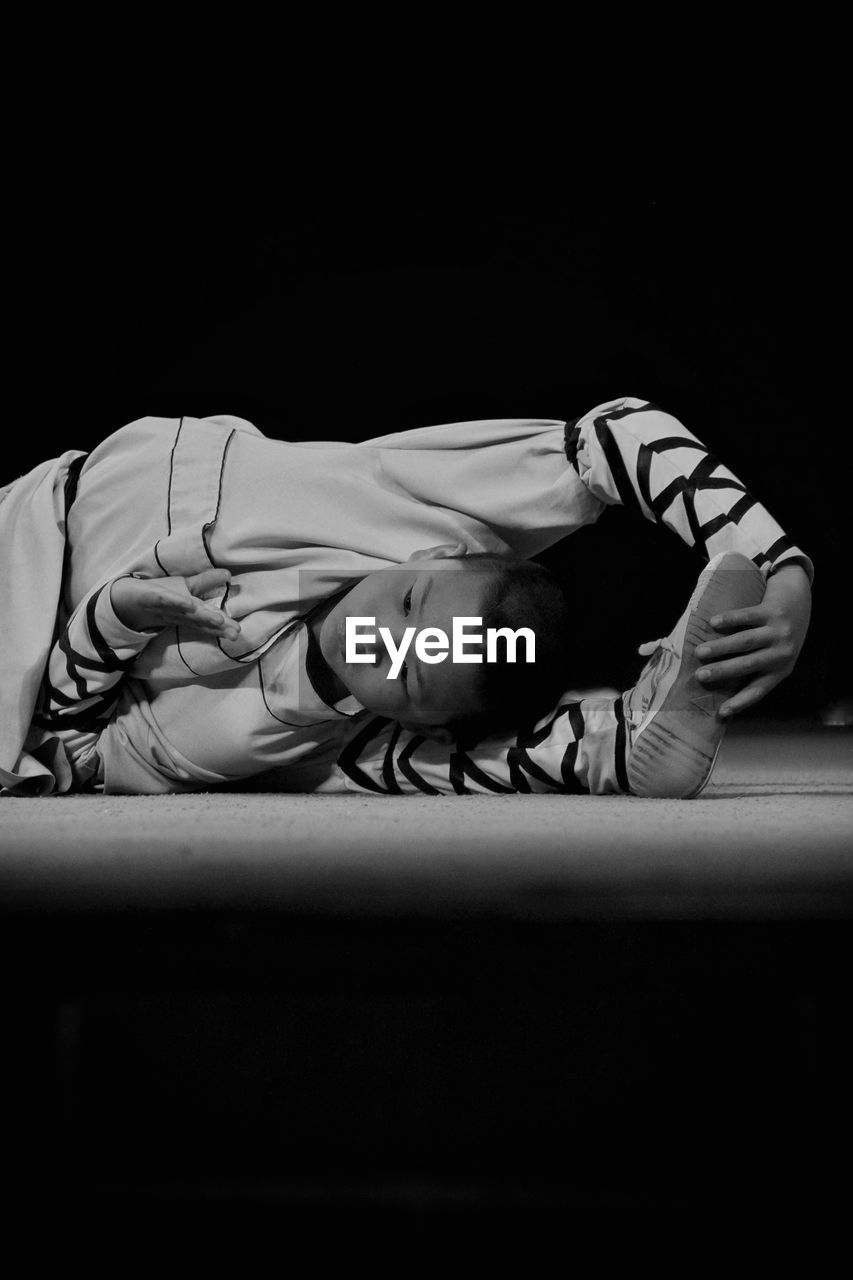 YOUNG MAN LYING DOWN ON BLACK BACKGROUND