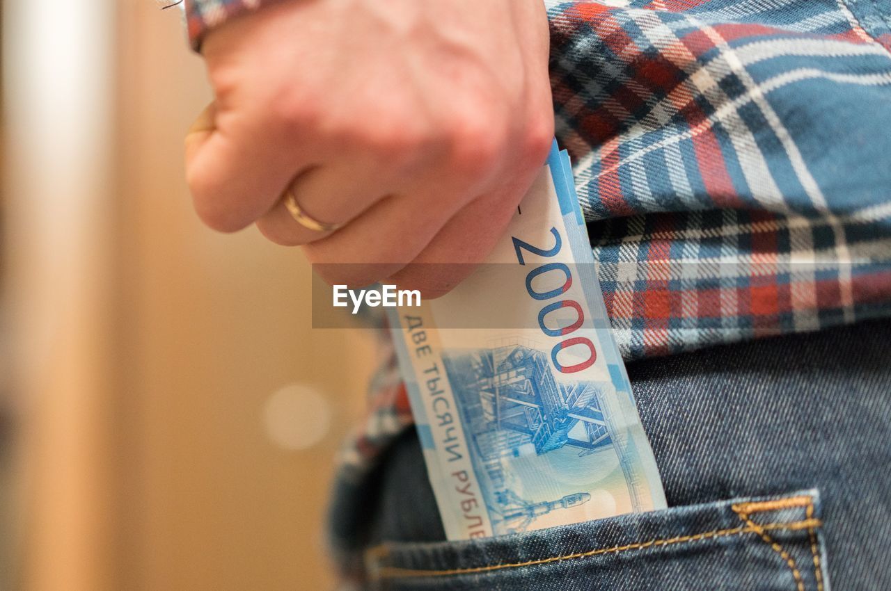 Midsection of man removing paper currency from back pocket