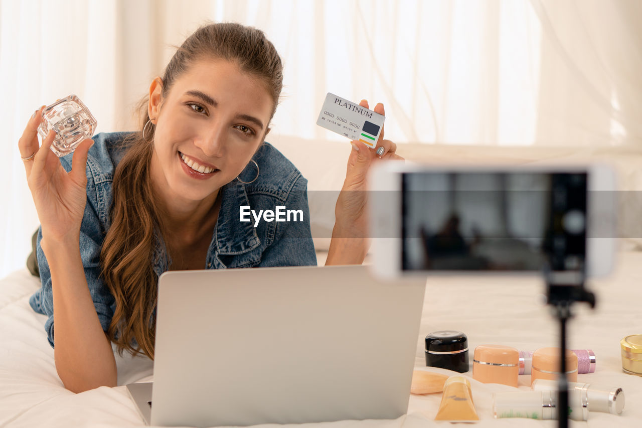 PORTRAIT OF YOUNG WOMAN USING LAPTOP AT HOME