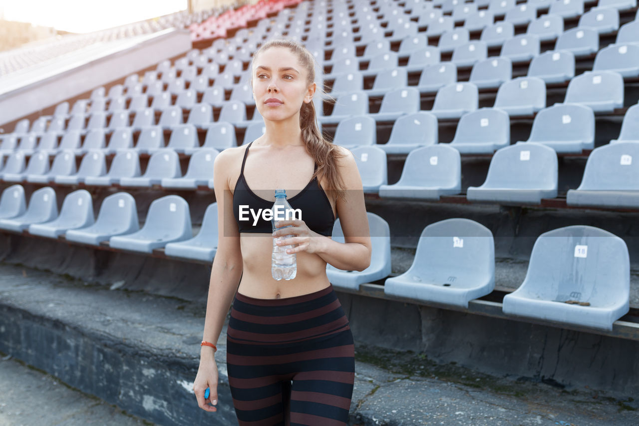 Woman standing against chairs at stadium