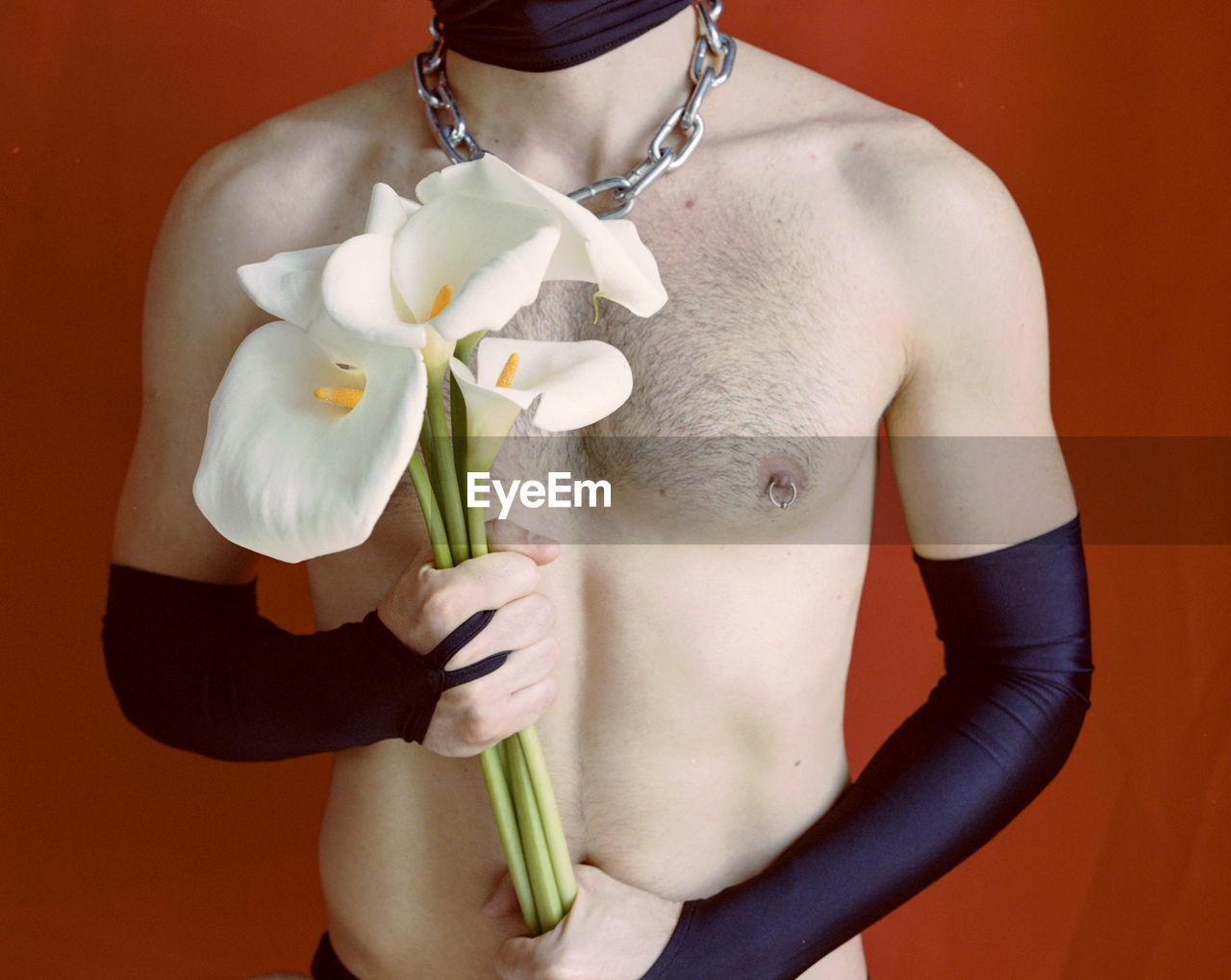 Midsection of man holding flowers against wall