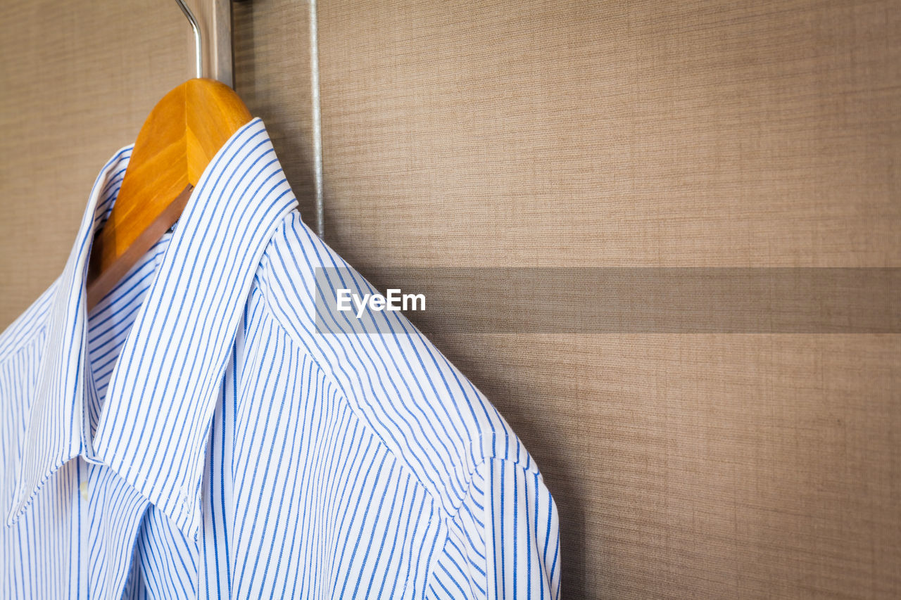 Close-up of blue shirt hanging on brown wall