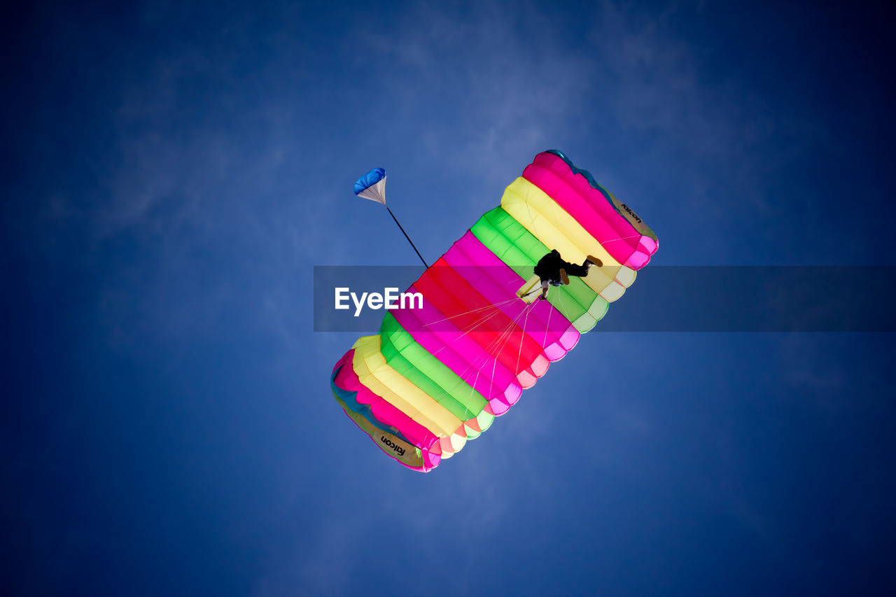 Low angle view of person paragliding against blue sky