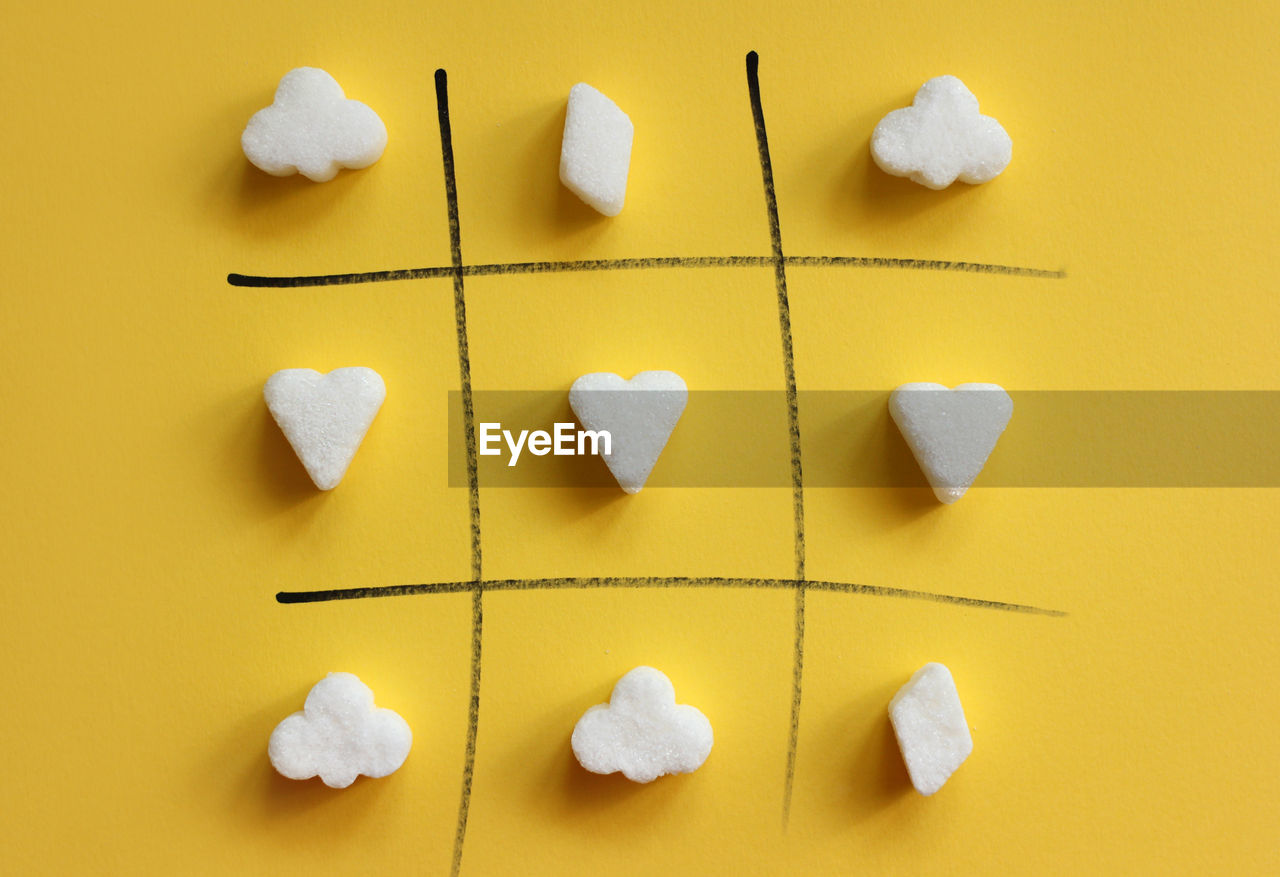 Sugar cubes shape in rows on yellow background