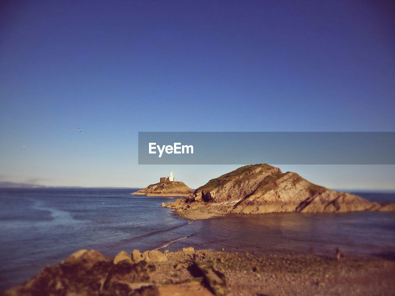 Idyllic shot of mumbles lighthouse in swansea bay against clear blue sky