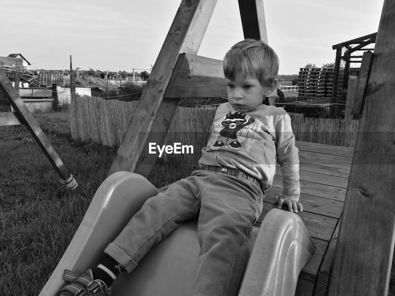 Boy looking away while sitting on play equipment