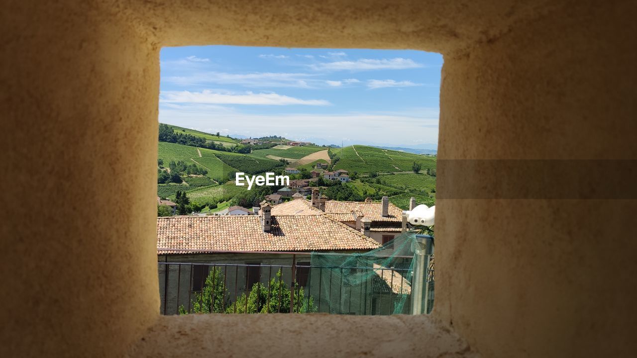 HOUSES AND TREES AGAINST SKY SEEN THROUGH WINDOW