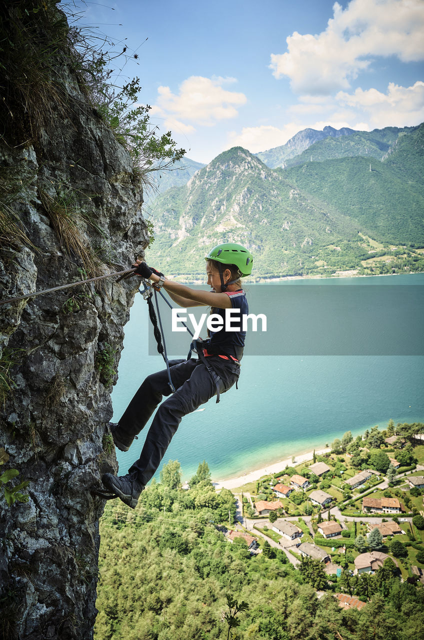 Girl climbing mountain with lake idro in background