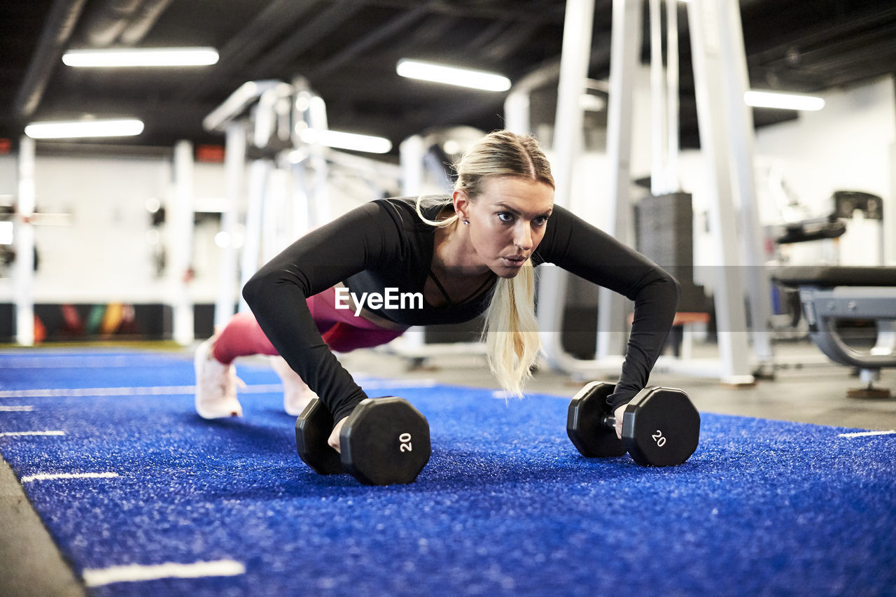 A woman doing push ups on the turf in the gym.