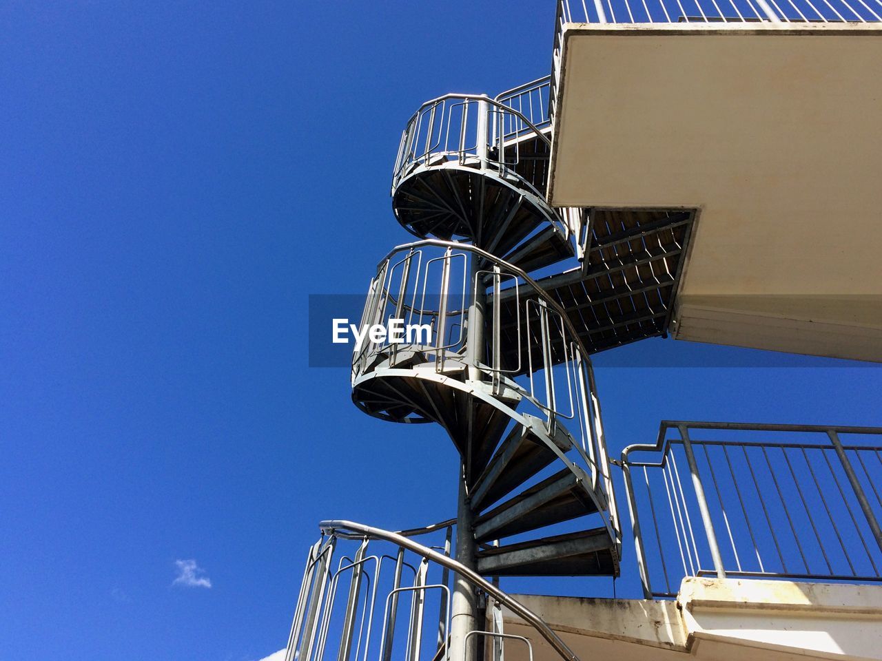 LOW ANGLE VIEW OF SPIRAL STAIRCASE AGAINST CLEAR BLUE SKY