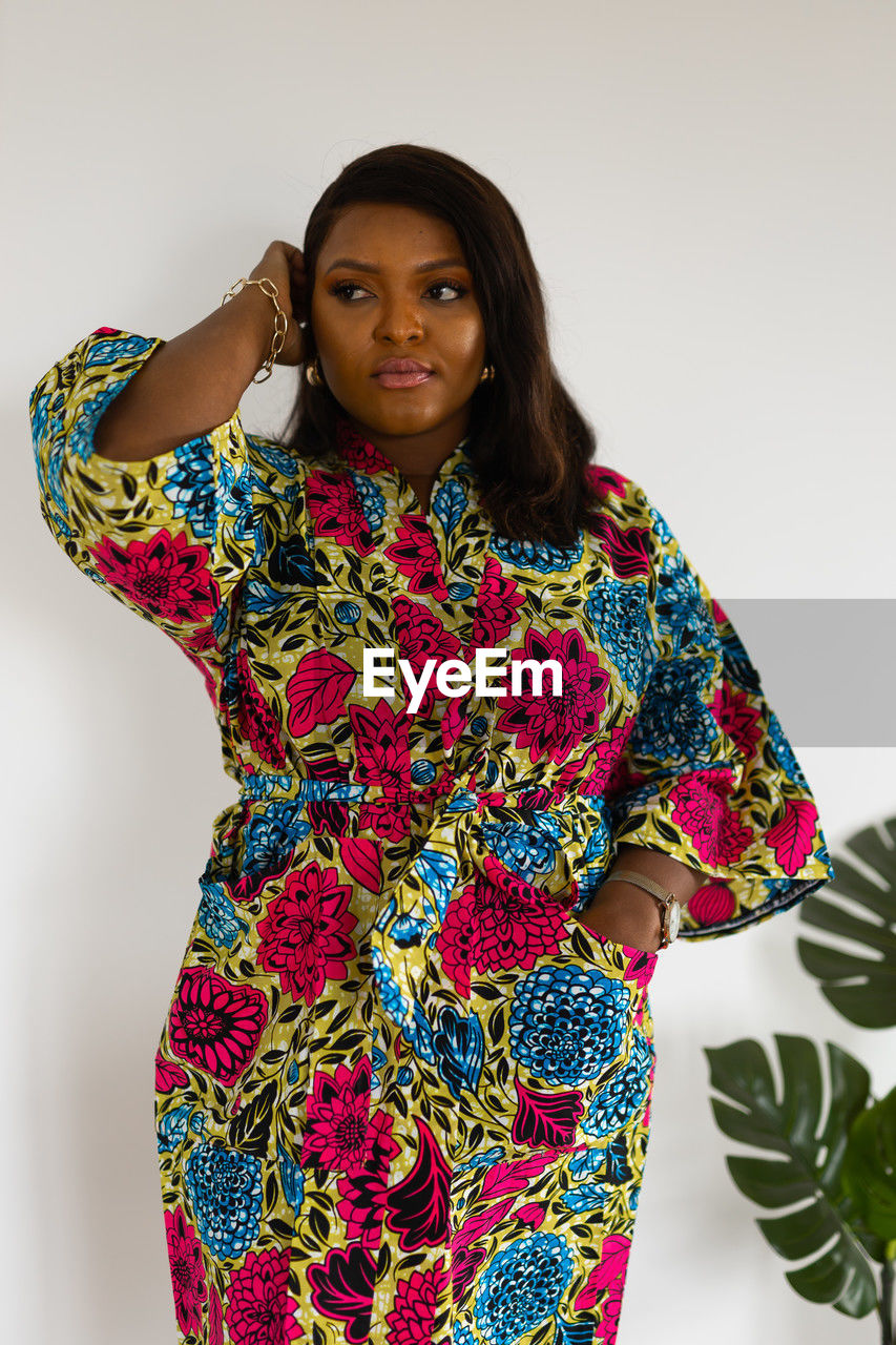 one person, sleeve, portrait, women, looking at camera, studio shot, adult, indoors, clothing, standing, pattern, dress, young adult, fashion, front view, three quarter length, white background, waist up, multi colored, hairstyle, smiling, emotion, floral pattern, female, outerwear, textile, photo shoot, black hair