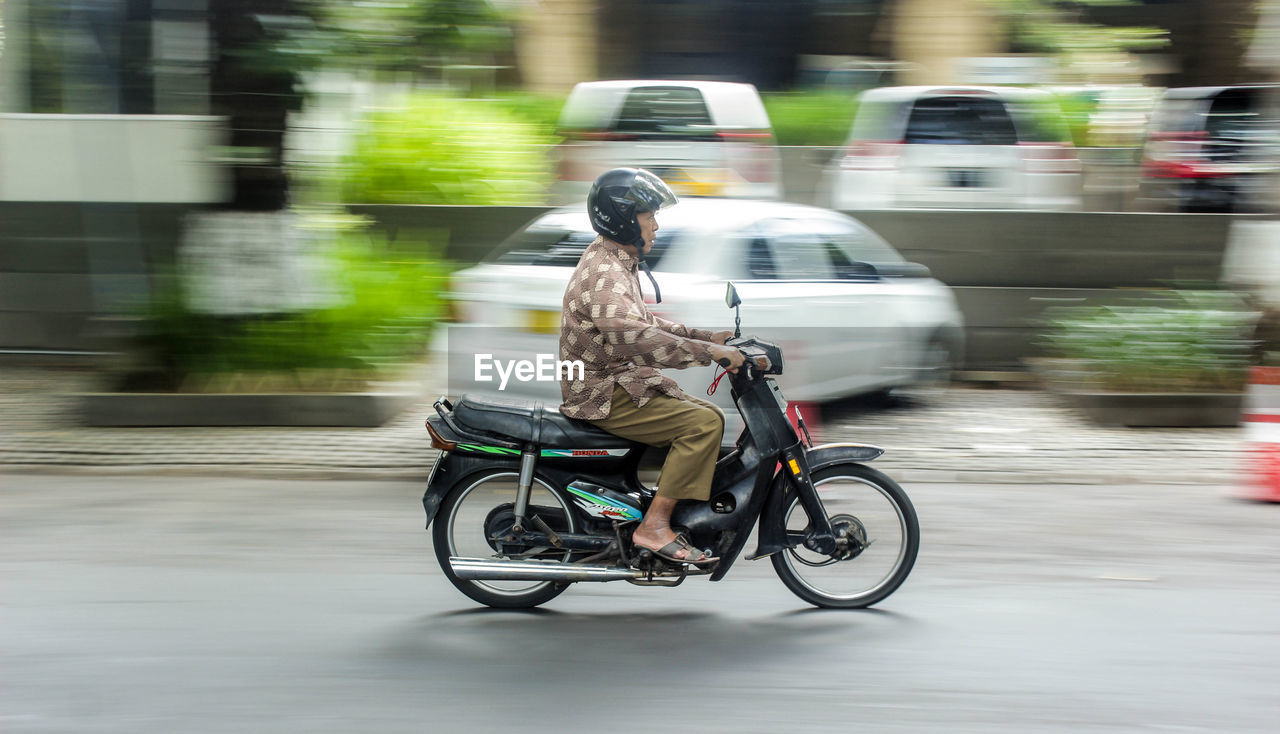 BLURRED MOTION OF MAN RIDING MOTORCYCLE ON ROAD