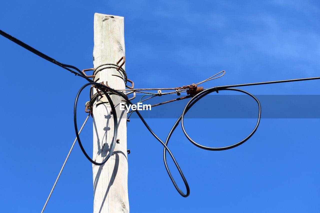 Low angle view of power lines against clear blue sky