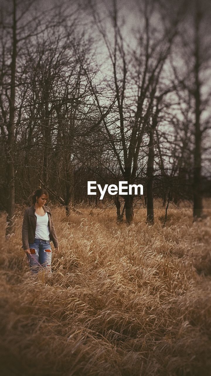 Young woman walking on amidst dried grass on field