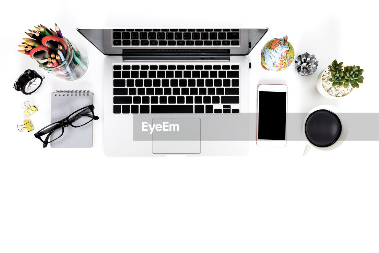 High angle view of laptop and coffee cup against white background