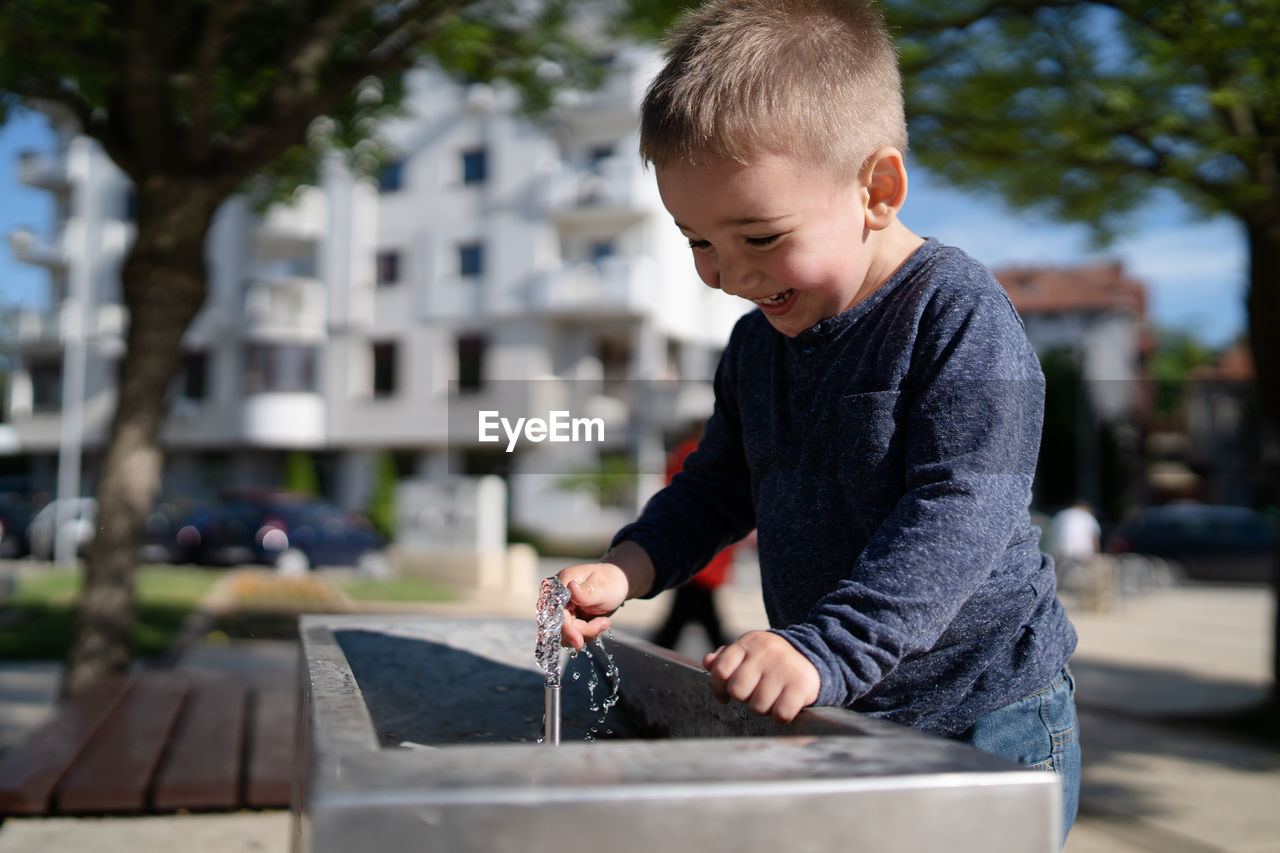 Cute boy drinking water at fountain