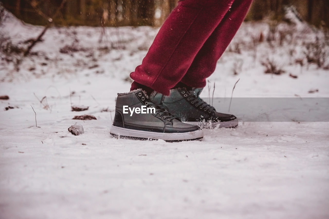 red, winter, footwear, low section, human leg, shoe, snow, spring, one person, limb, human limb, cold temperature, white, nature, adult, day, selective focus, lifestyles, clothing, human foot, leisure activity, women, standing, black, outdoors, pink, winter sports, land, freezing