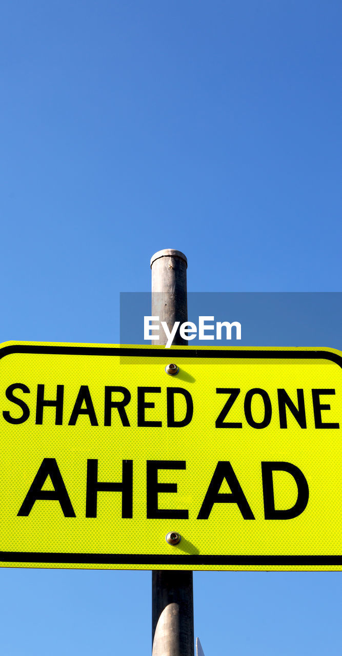 LOW ANGLE VIEW OF SIGN AGAINST BLUE SKY
