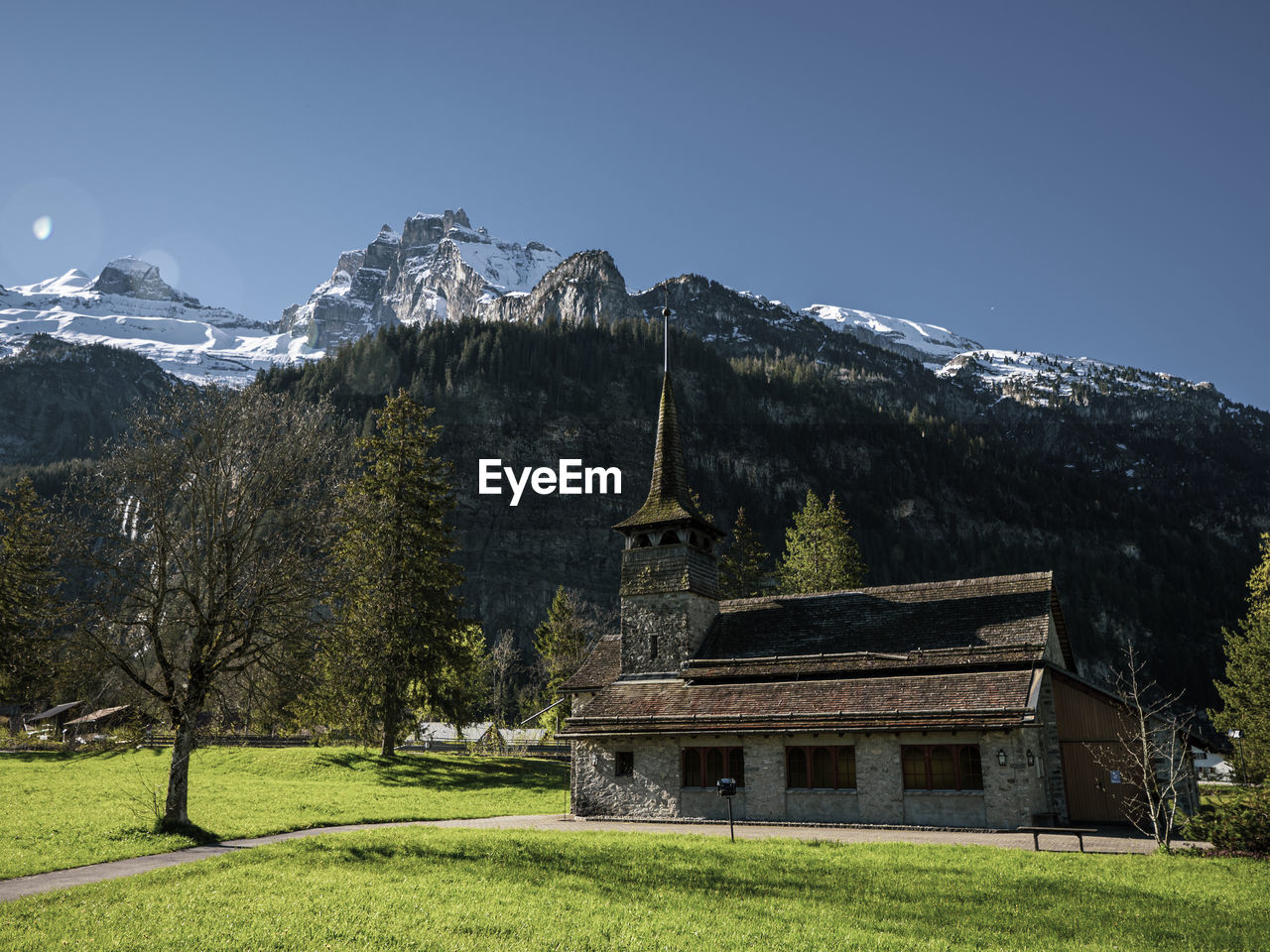 Beautiful old rustic alpine church and snow capped alpine mountains.