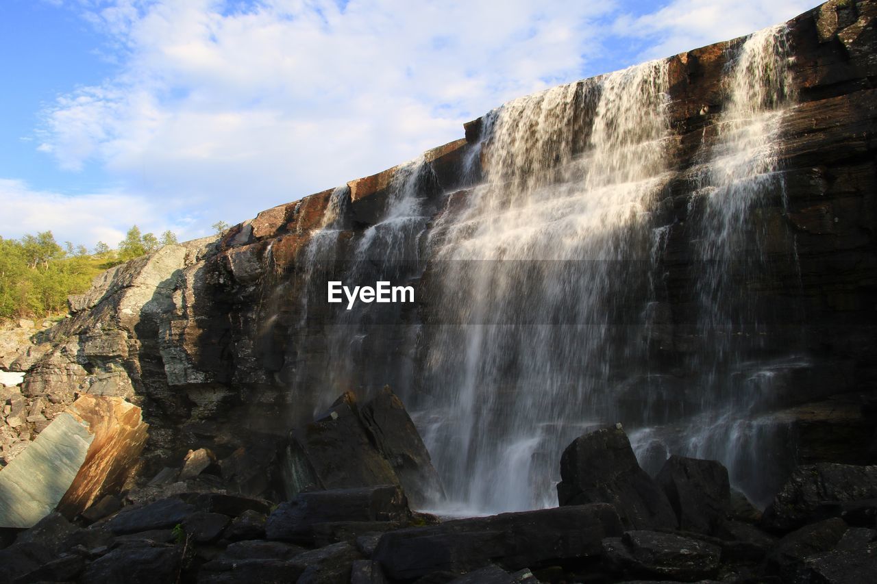 VIEW OF WATERFALL WITH ROCKS IN FOREGROUND