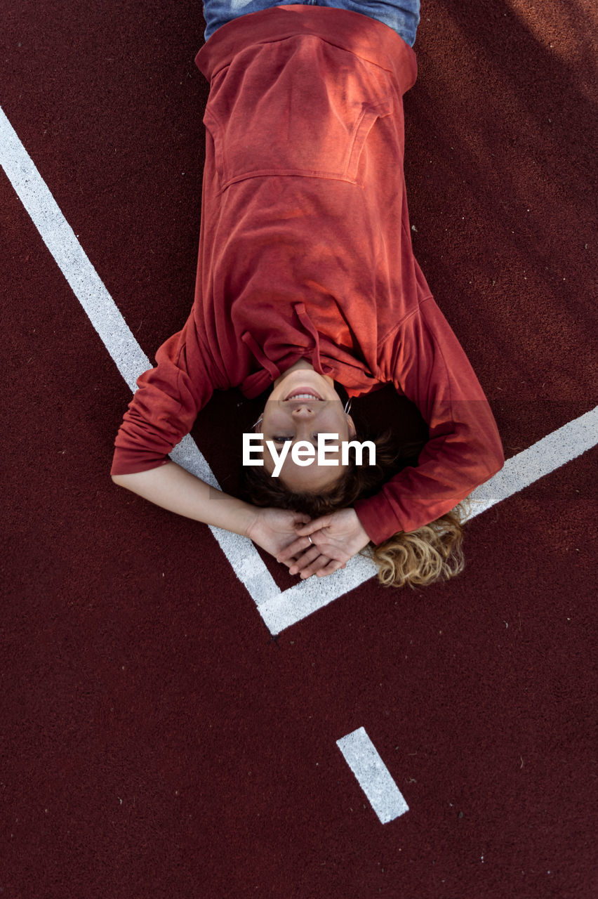 High angle portrait of young woman lying down on running track