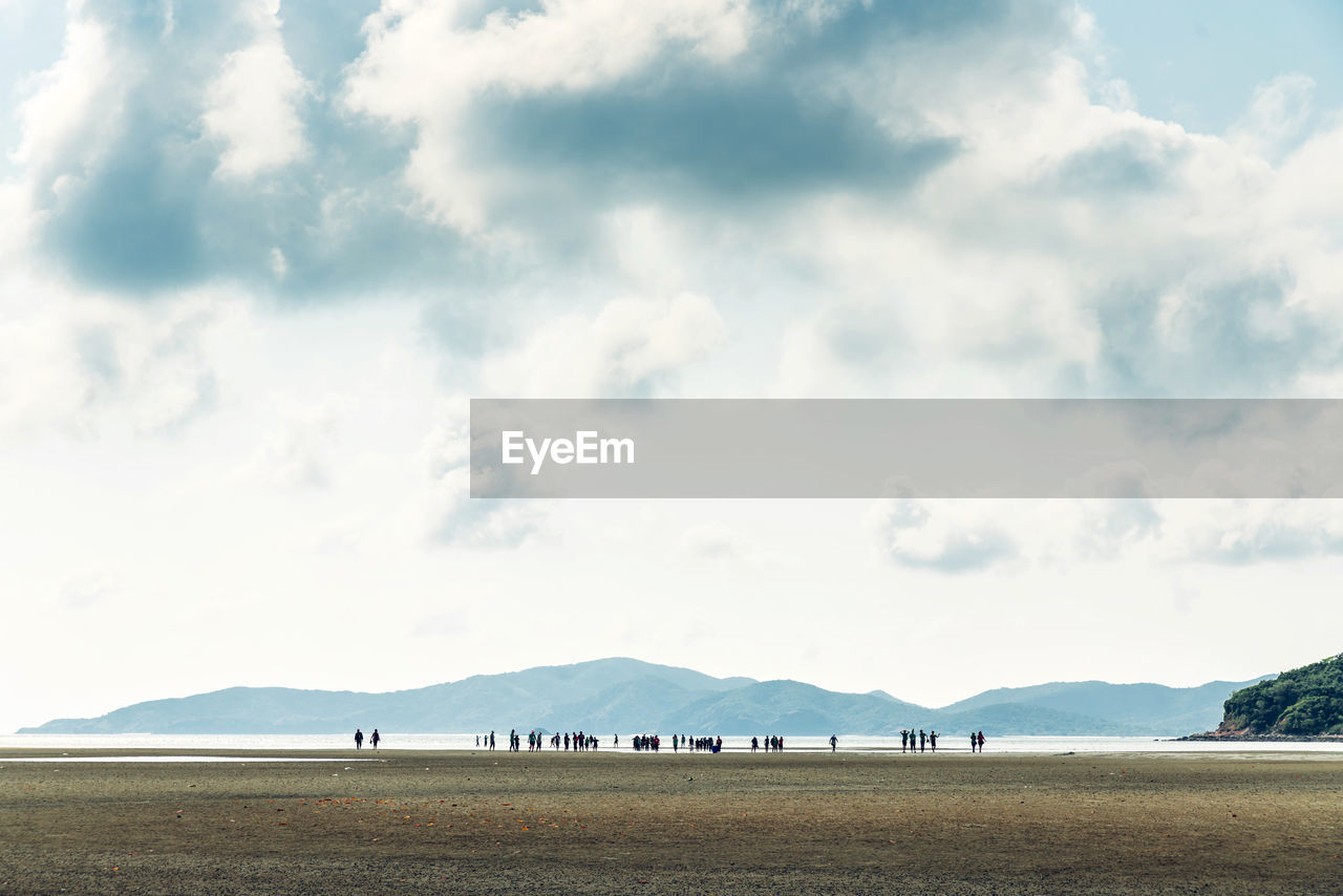 People on land by sea against sky