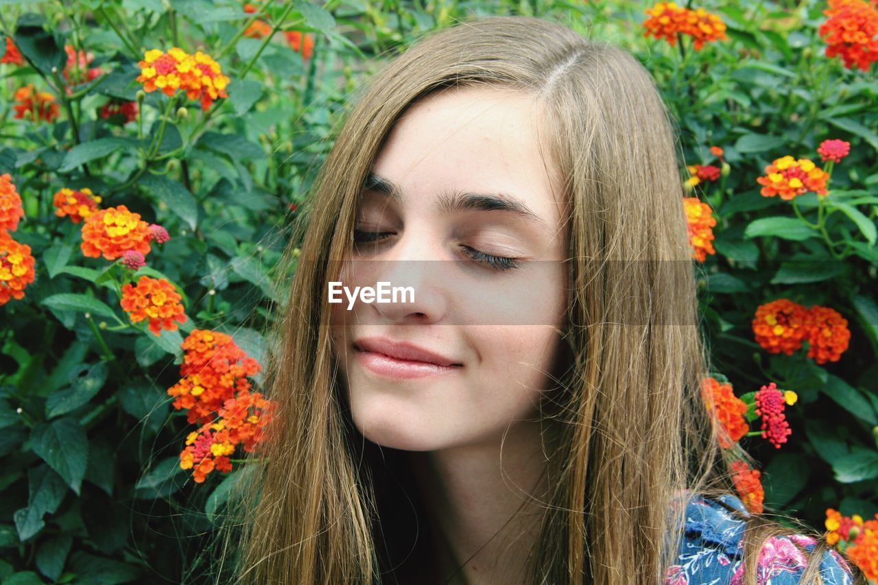 Close-up of young woman with eyes closed by lantana camara