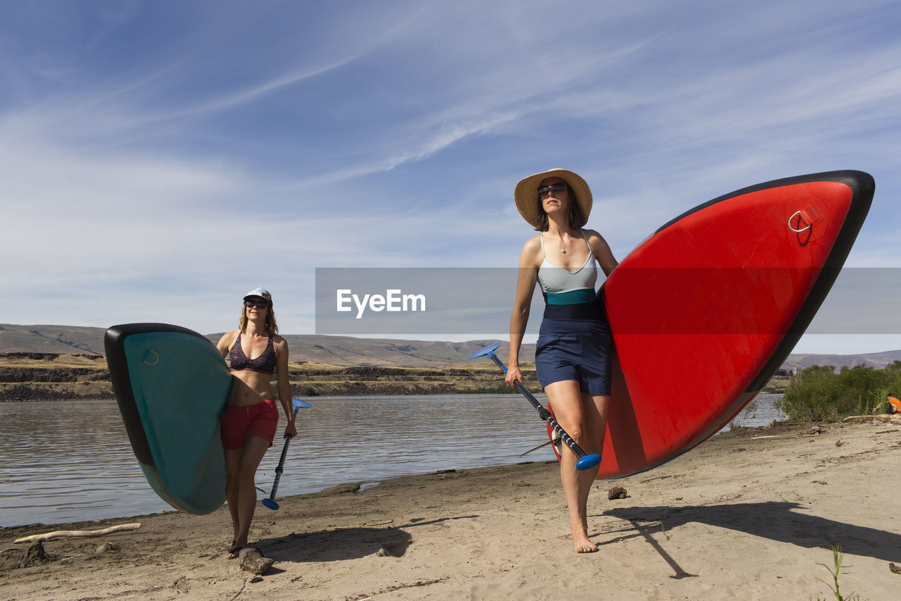 Two women carry their sups from the columbia river in oregon.