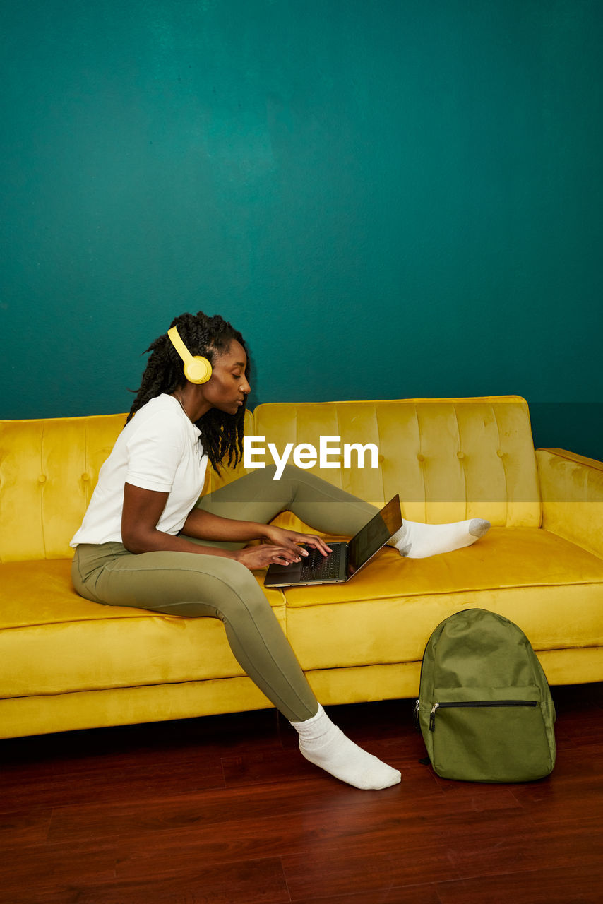 Black styled student sitting on a sofa with a computer