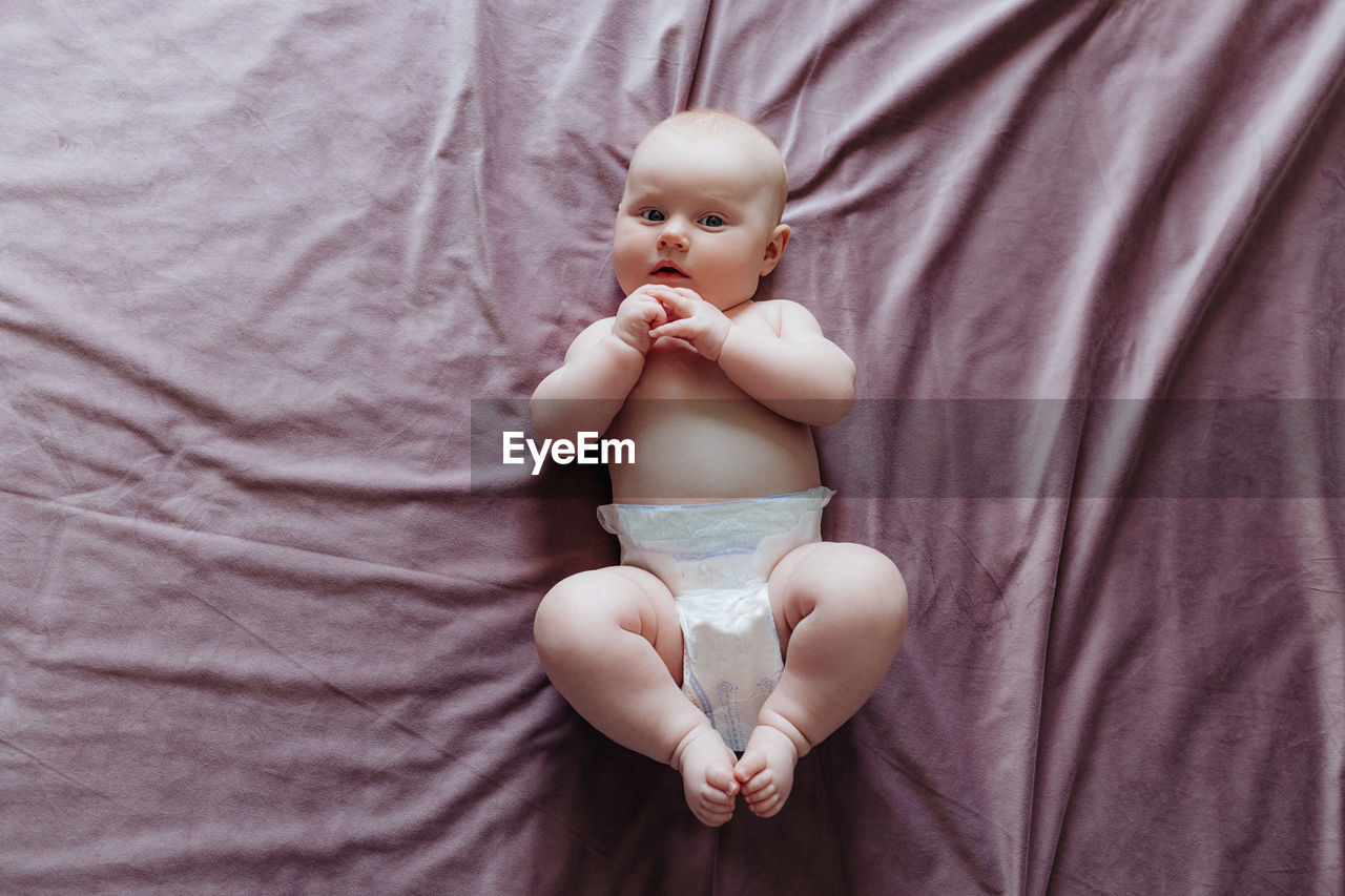 The child lies on the bed and looks up, top view