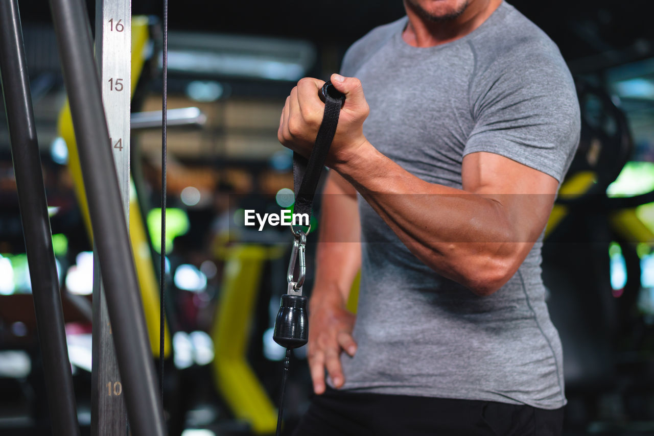 MIDSECTION OF MAN HOLDING CAMERA WHILE STANDING IN BUS