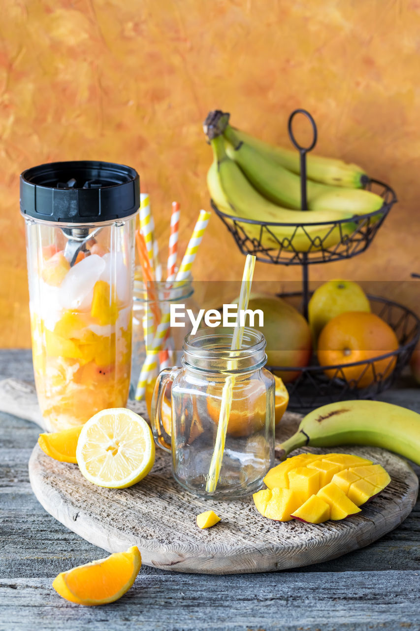A blender container filled with ingredients to make a citrus mango smoothie.