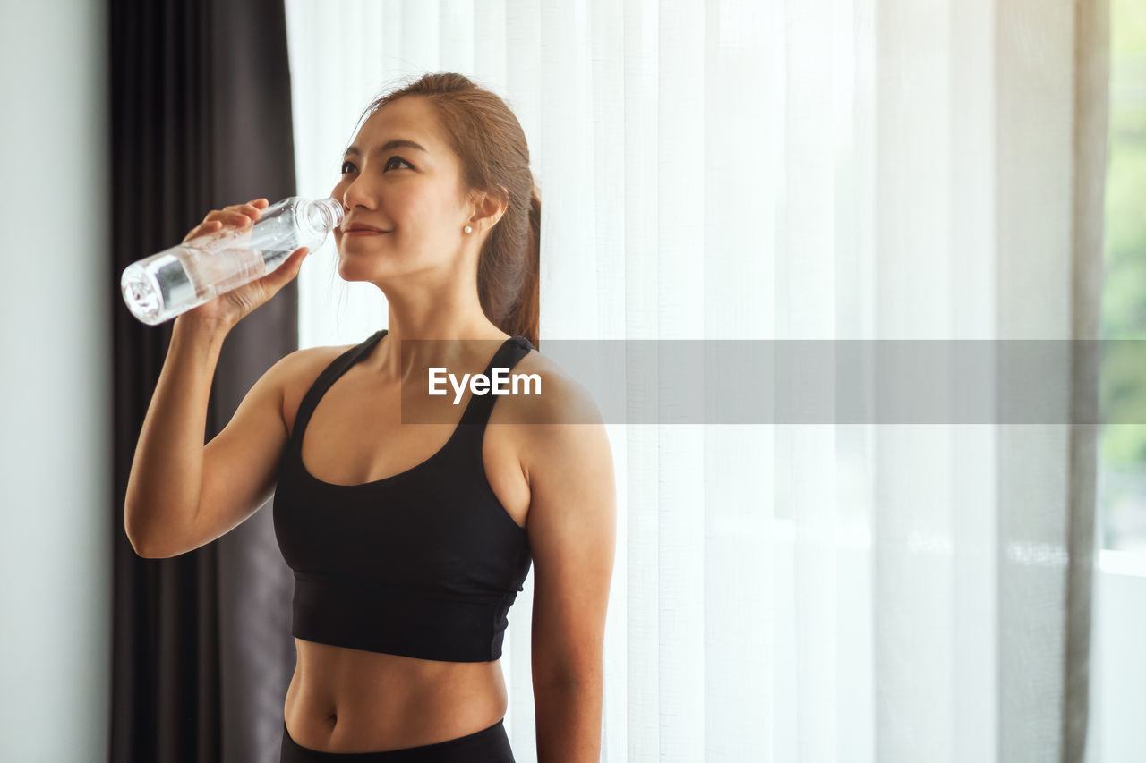 Young woman drinking water from bottle