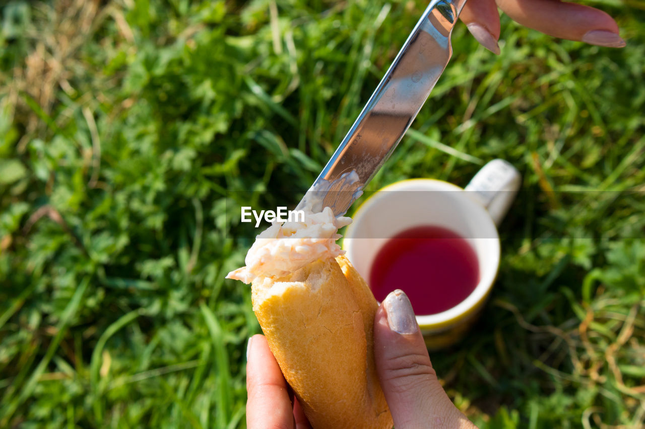 Cropped image of woman applying butter on bread at yard