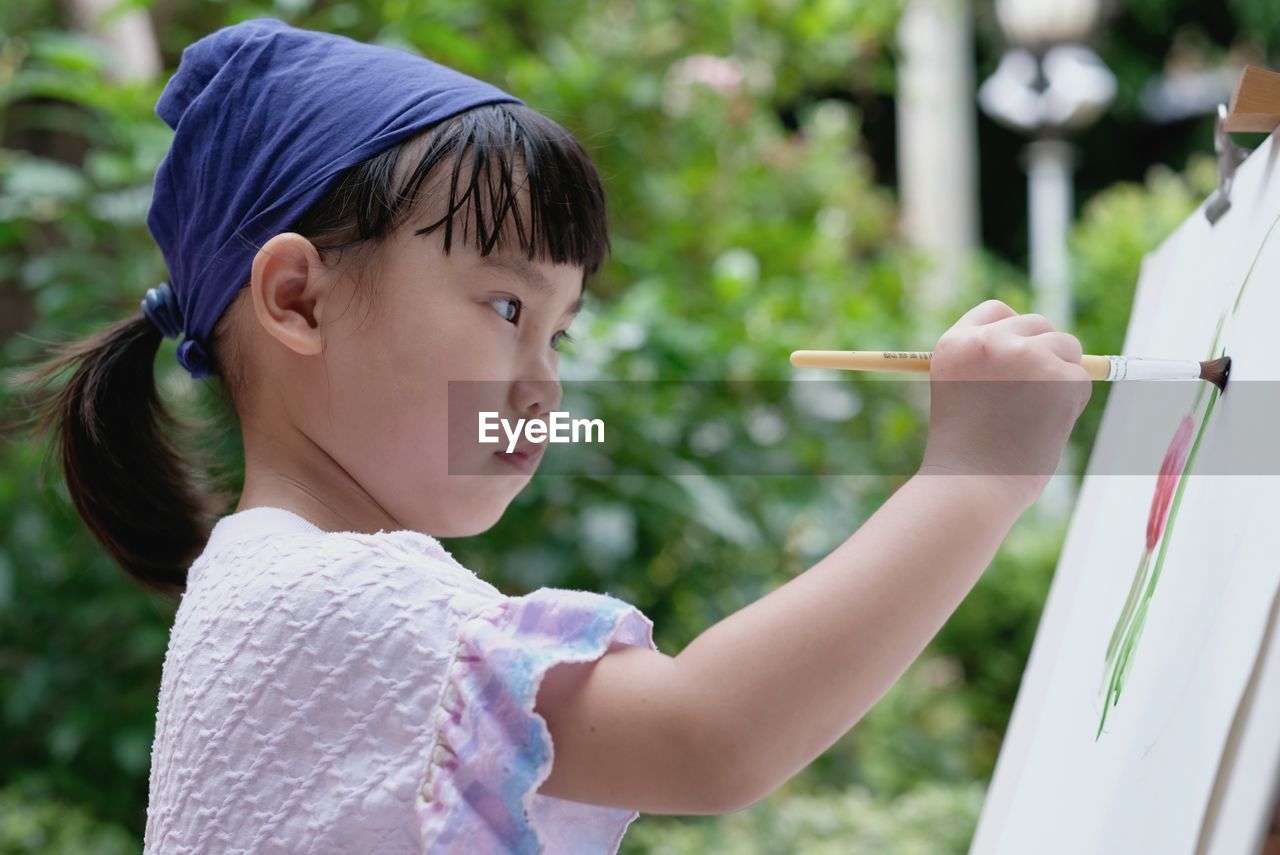 SIDE VIEW PORTRAIT OF CUTE BABY BOY HOLDING OUTDOORS