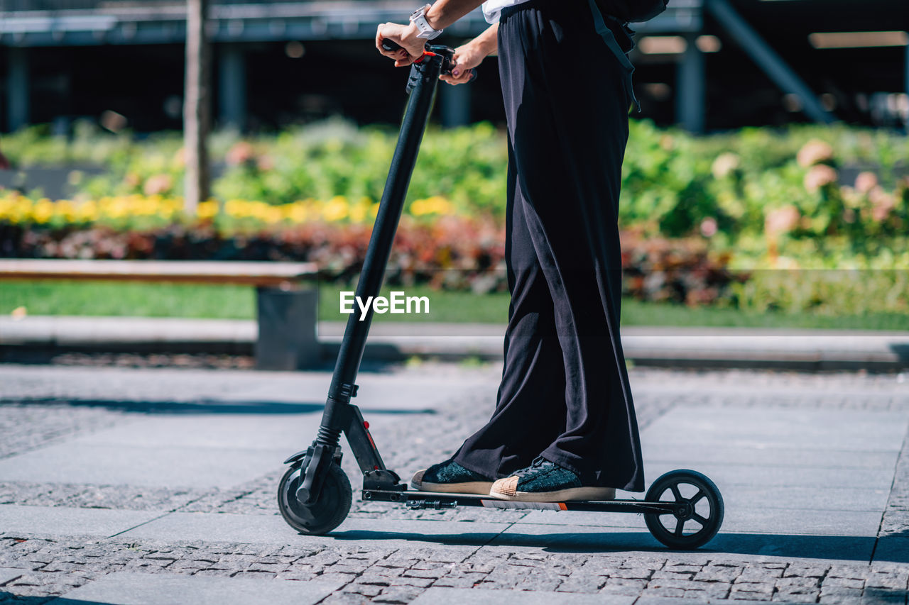 Low section of woman riding electric scooter on footpath