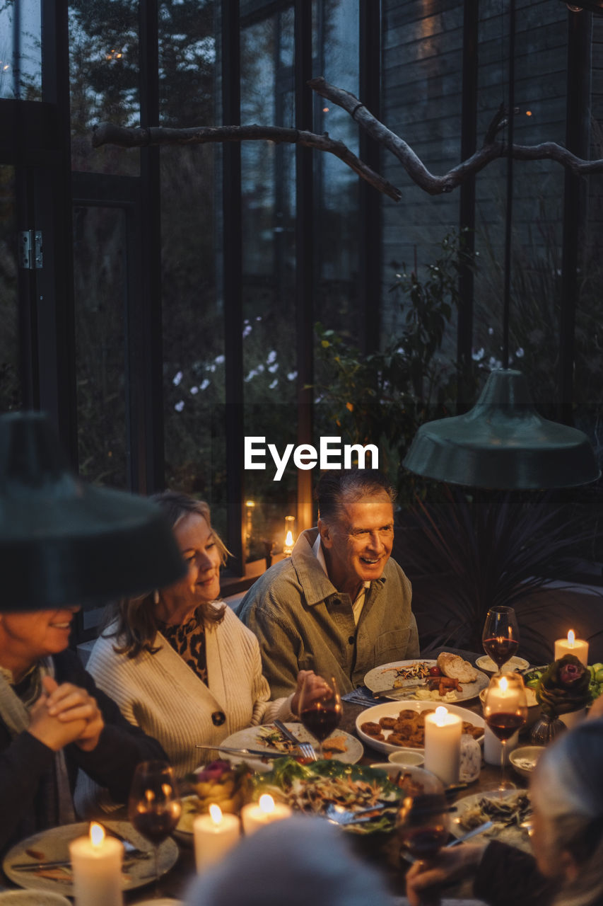 Happy senior male and female friends having food at dinner party