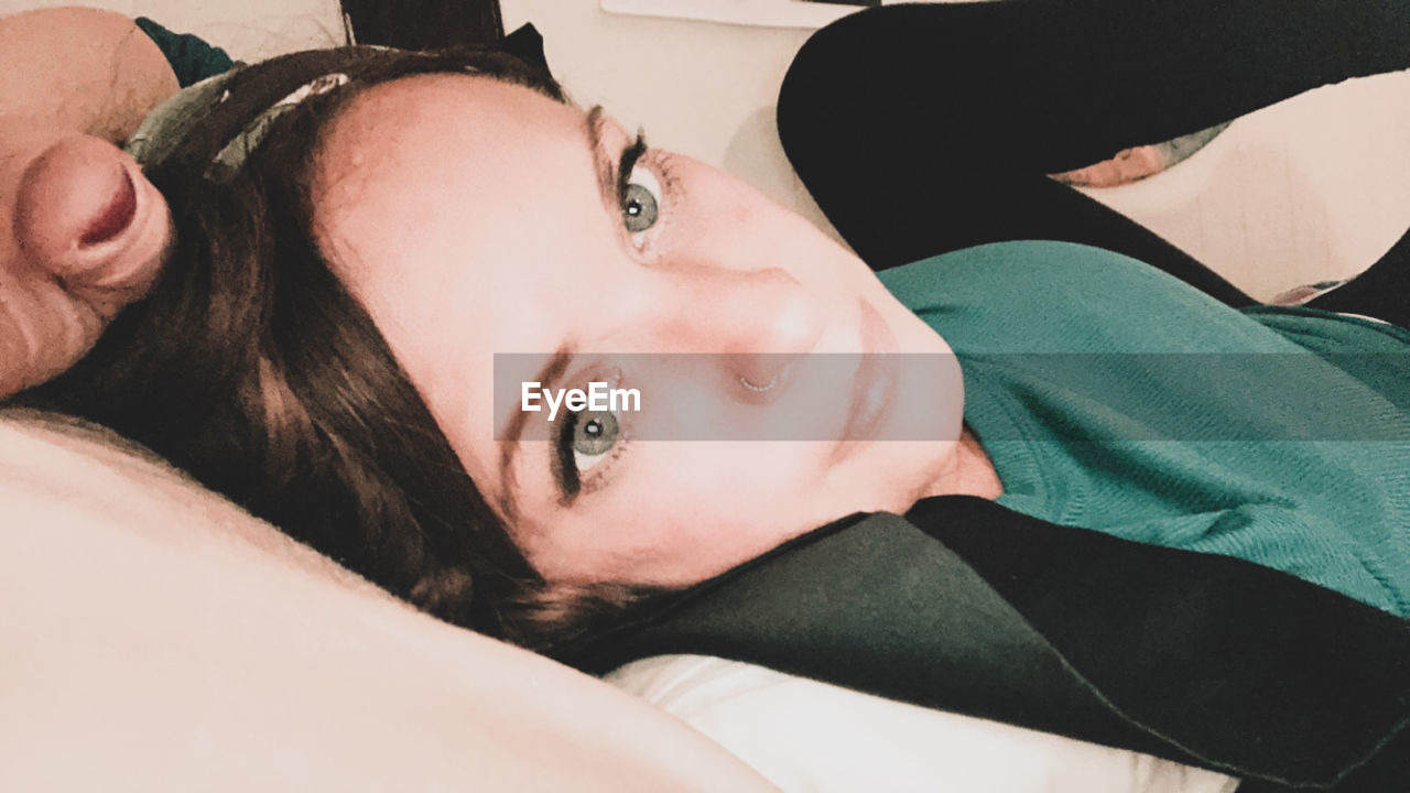 PORTRAIT OF YOUNG WOMAN LYING DOWN ON BED