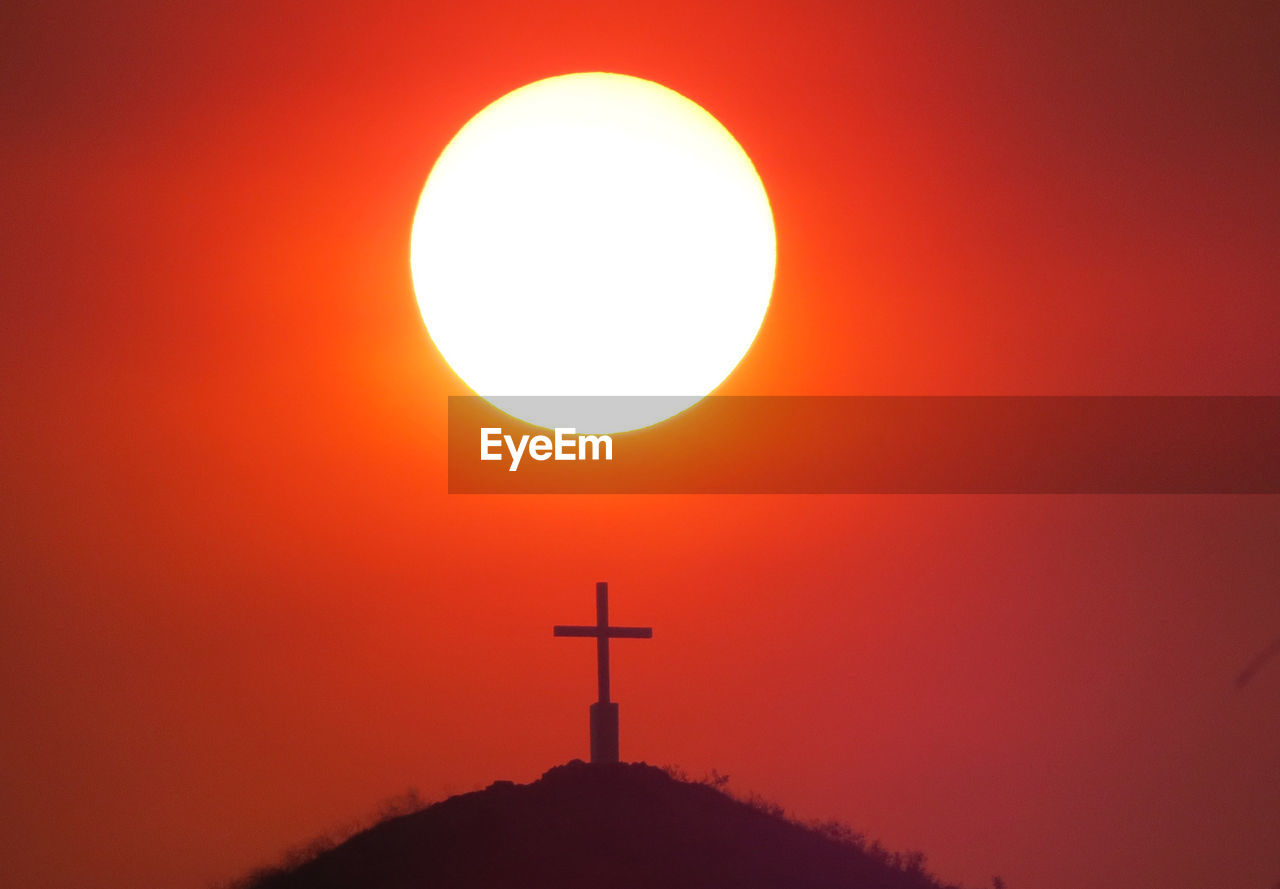 Silhouette cross against sky during sunset