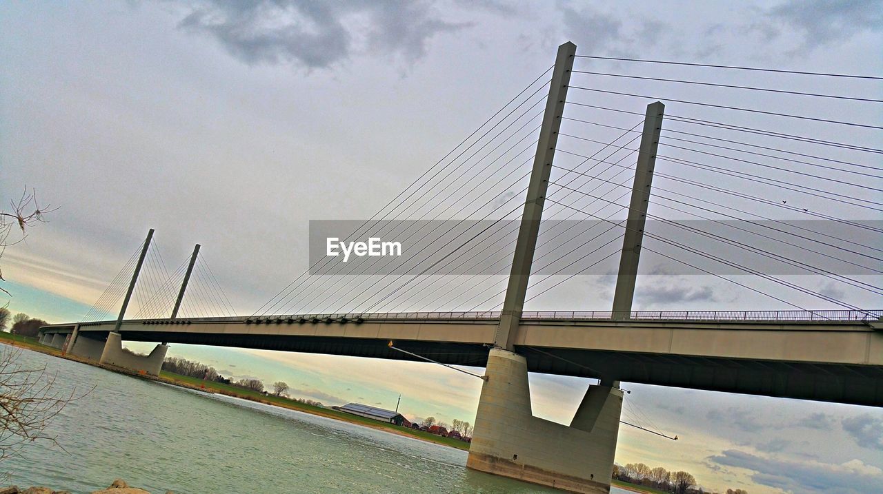 SUSPENSION BRIDGE AGAINST CLOUDY SKY