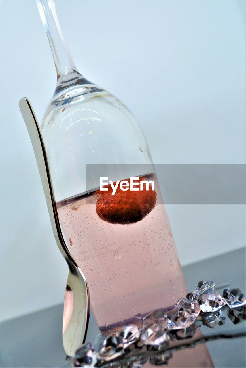 CLOSE-UP OF DRINK IN GLASS ON TABLE AGAINST WHITE BACKGROUND