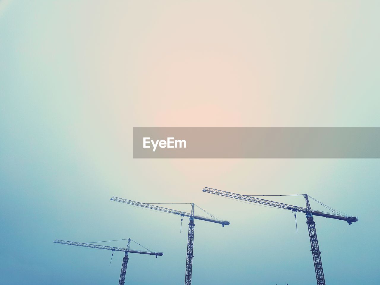 Low angle view of cranes against sky during sunset