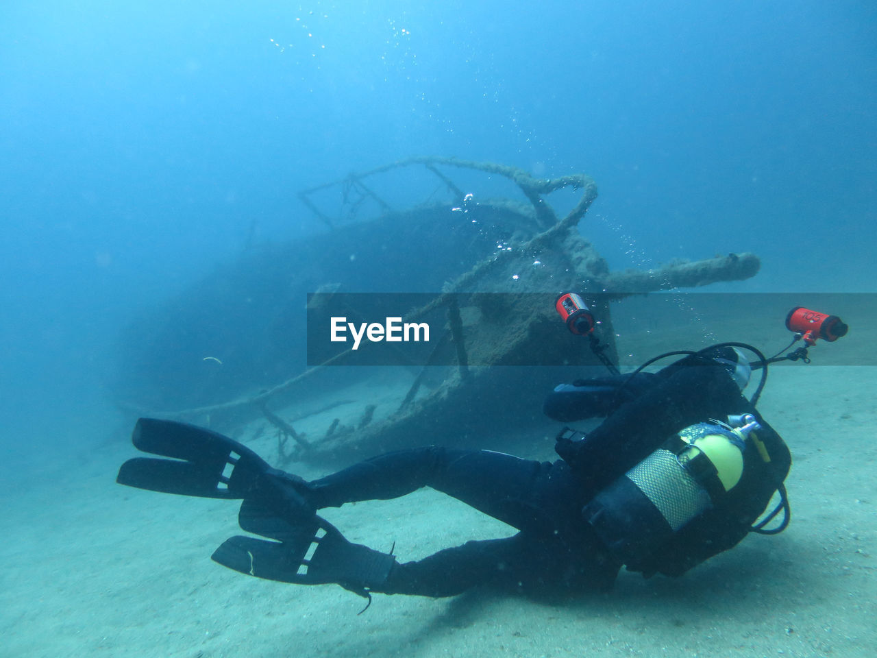 Man scuba diving by sunken boat undersea