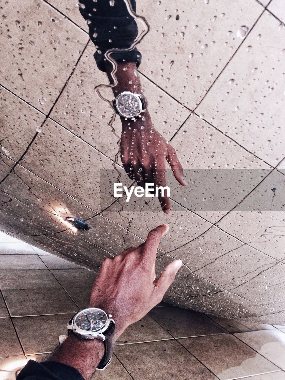 Cropped image of man touching wet glass wall