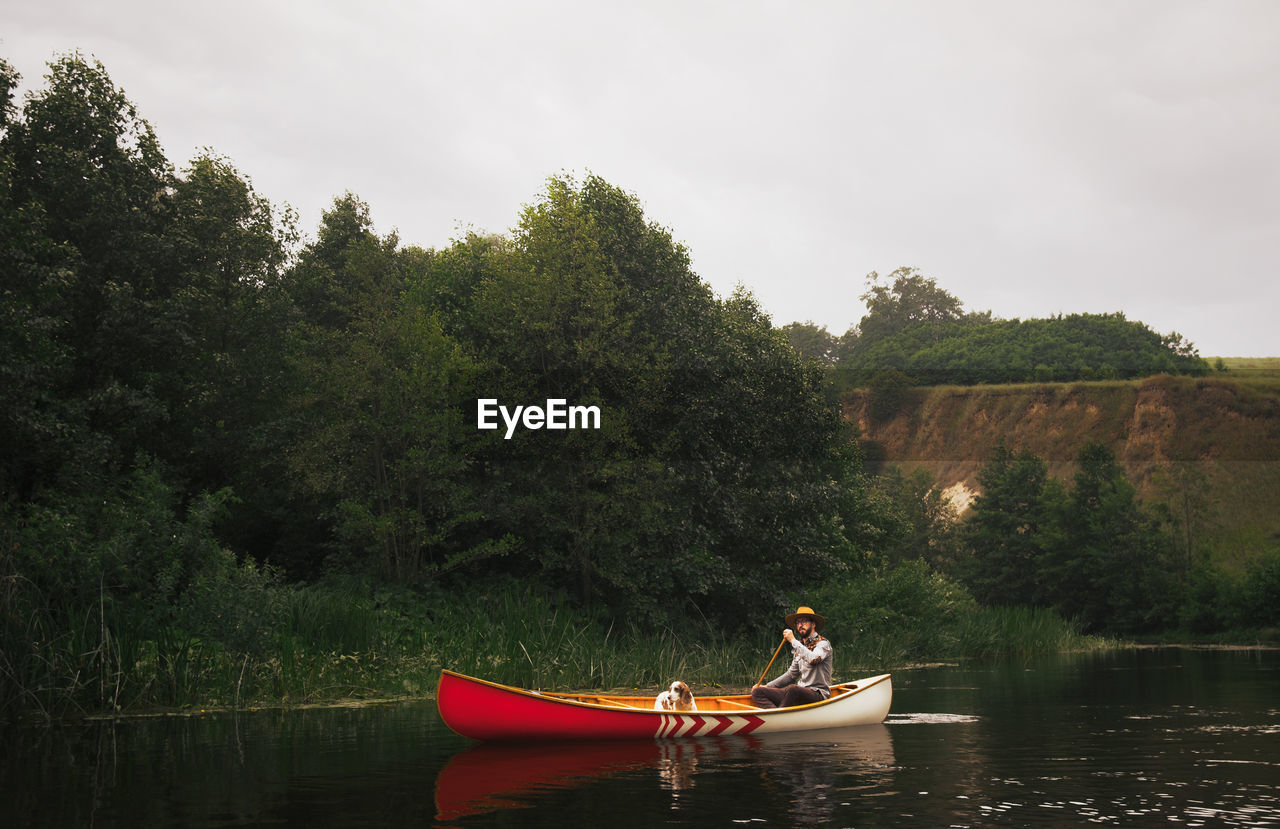 Man in canoe with his dog in a beatiful nature park on the river