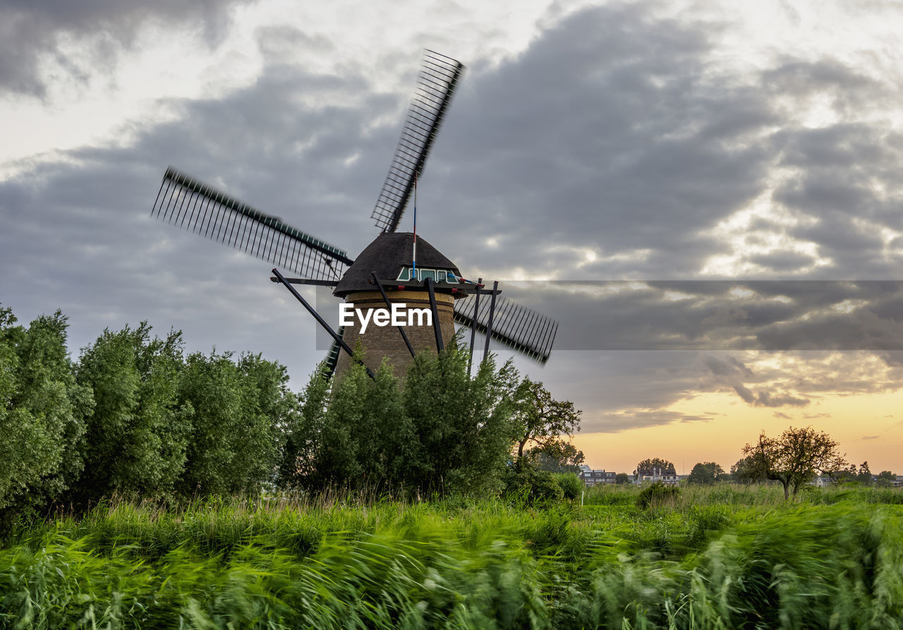 TRADITIONAL WINDMILLS ON FIELD AGAINST SKY