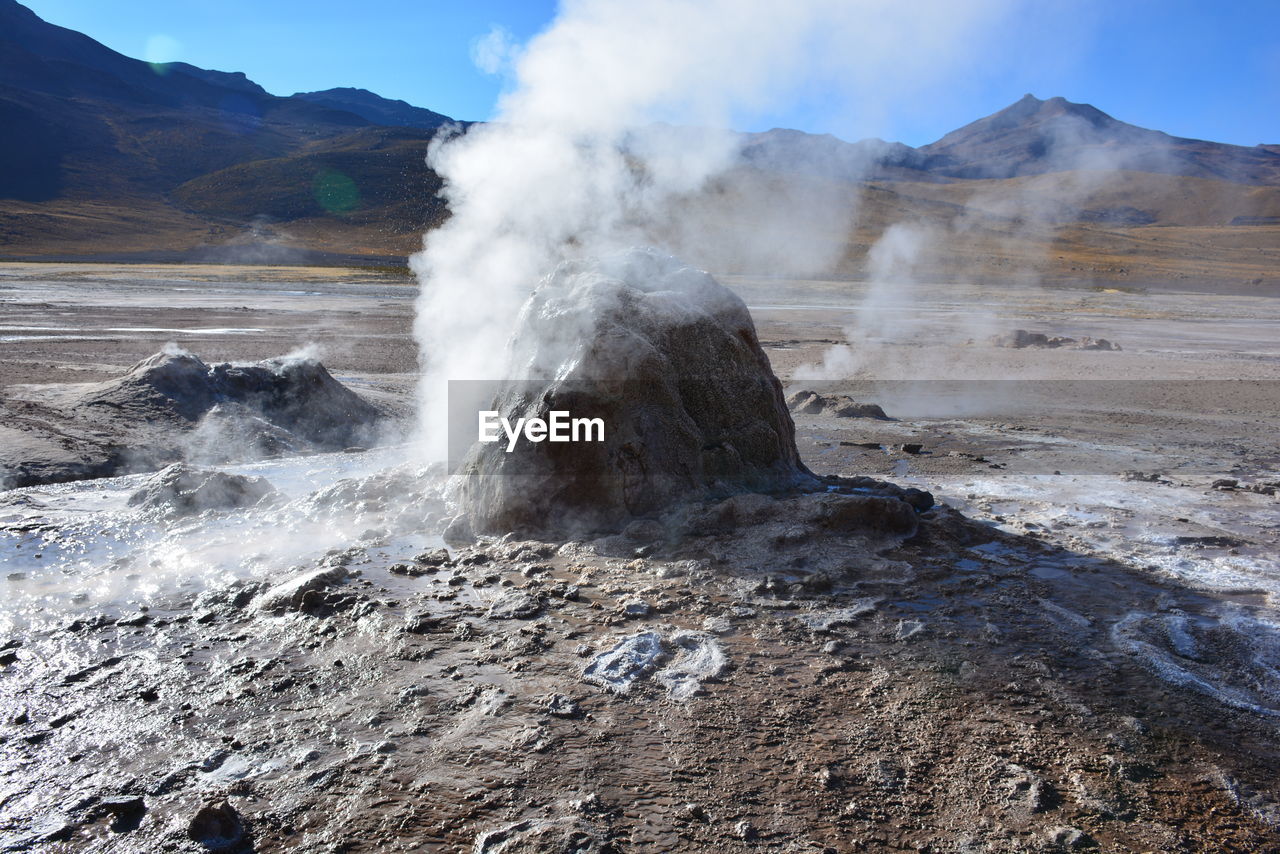 Steam emitting from geyser by rock formation