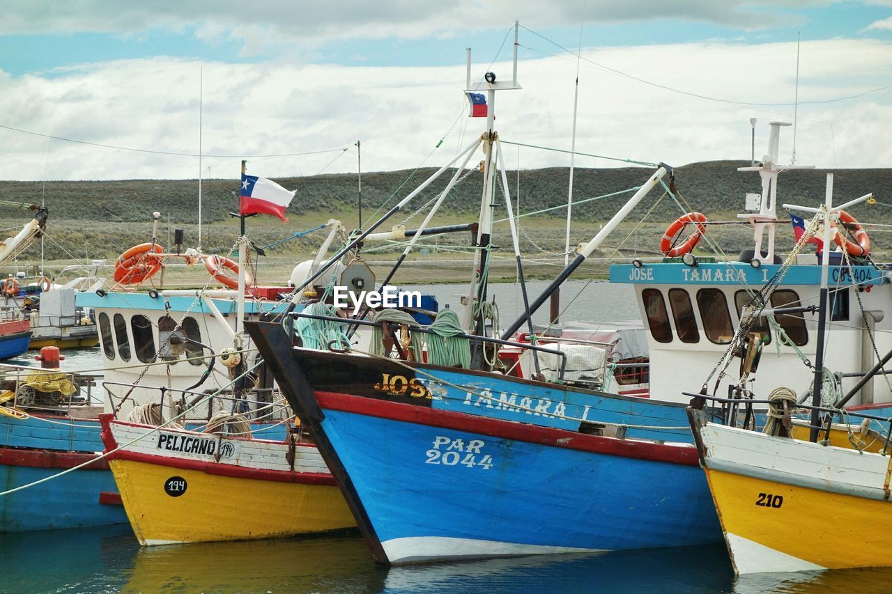 Boats moored at harbor in sea against sky