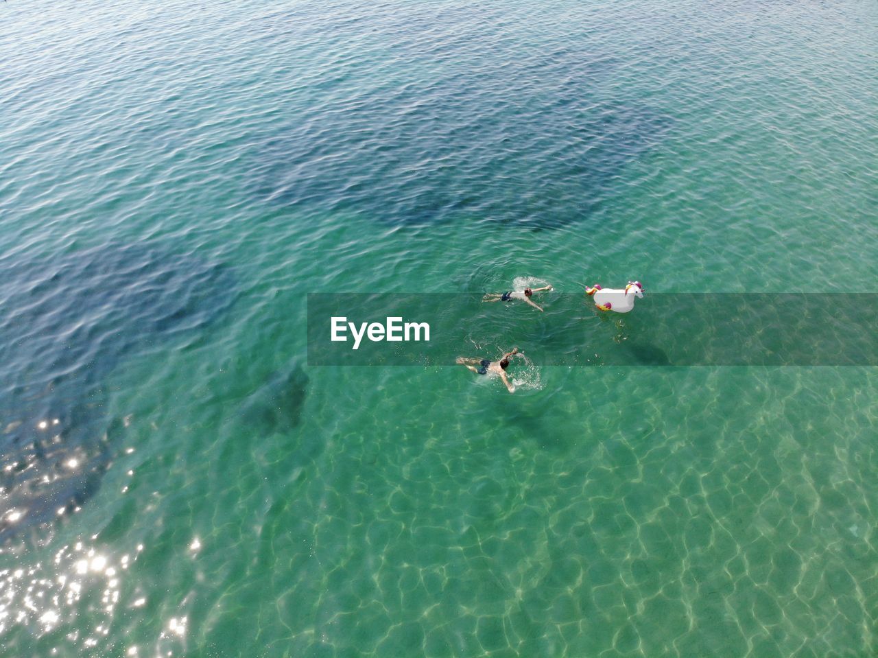 HIGH ANGLE VIEW OF TWO PEOPLE SWIMMING IN SEA